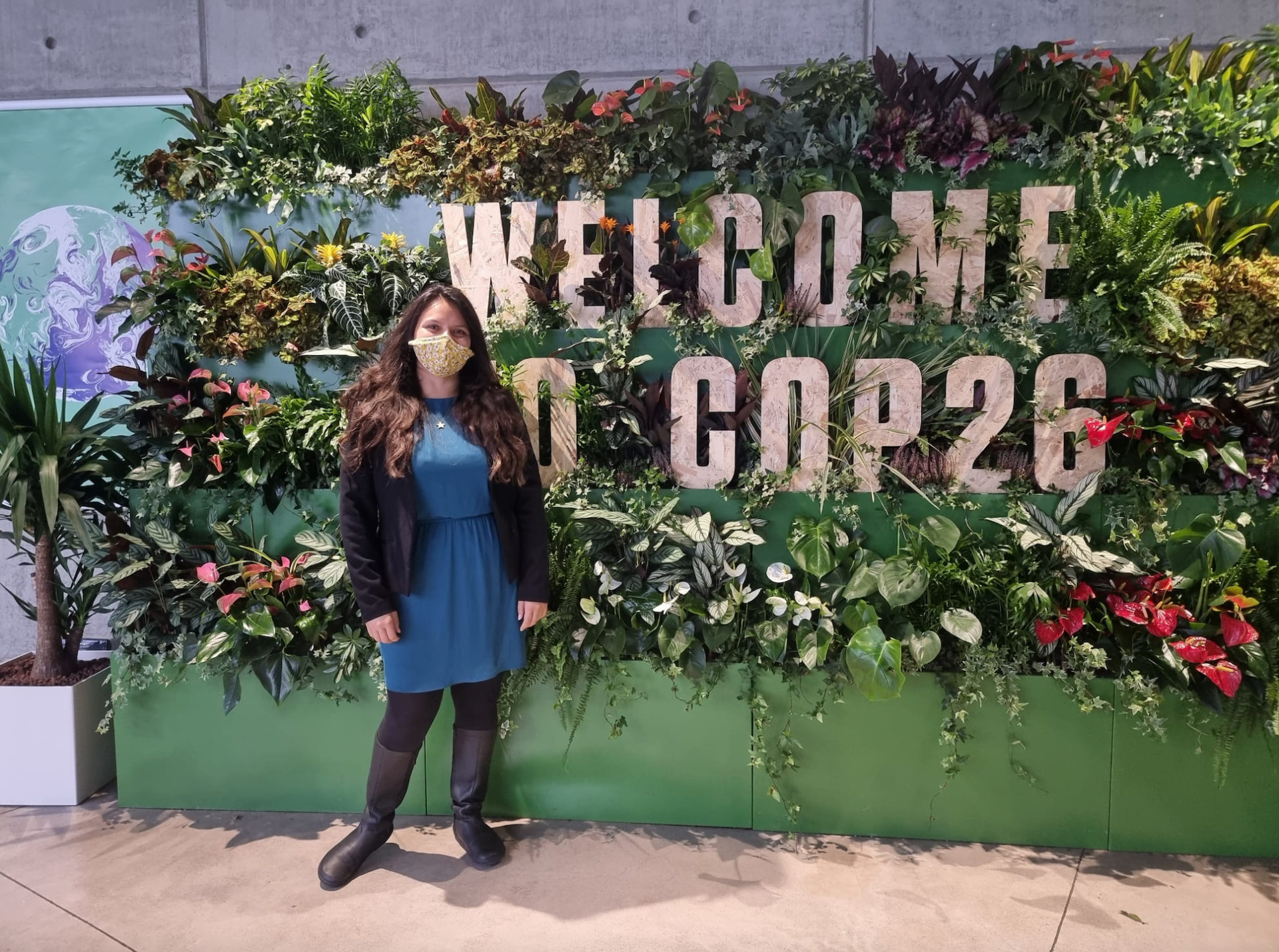 Olivia Reddy in front of the Welcome to COP26 Sign